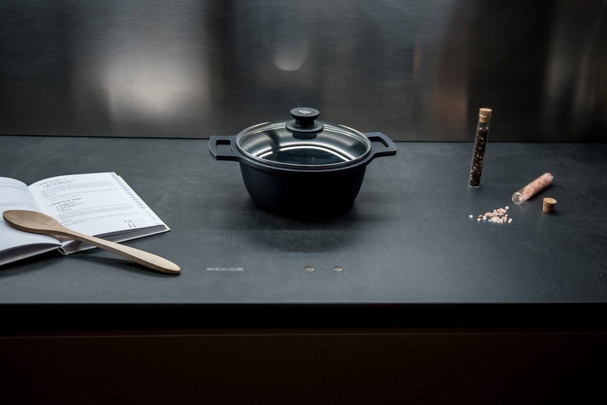 Unsichtbares Induktionskochfeld mit grauer Oberfläche auf der ein schwarzer Kochtopf steht